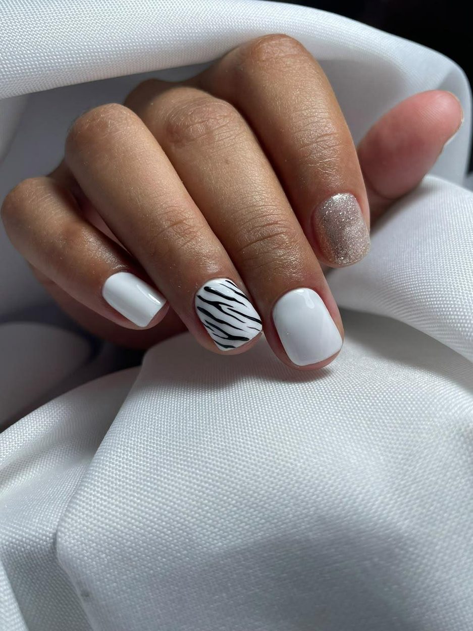 Uñas blancas con una uña cebra y una con glitter
