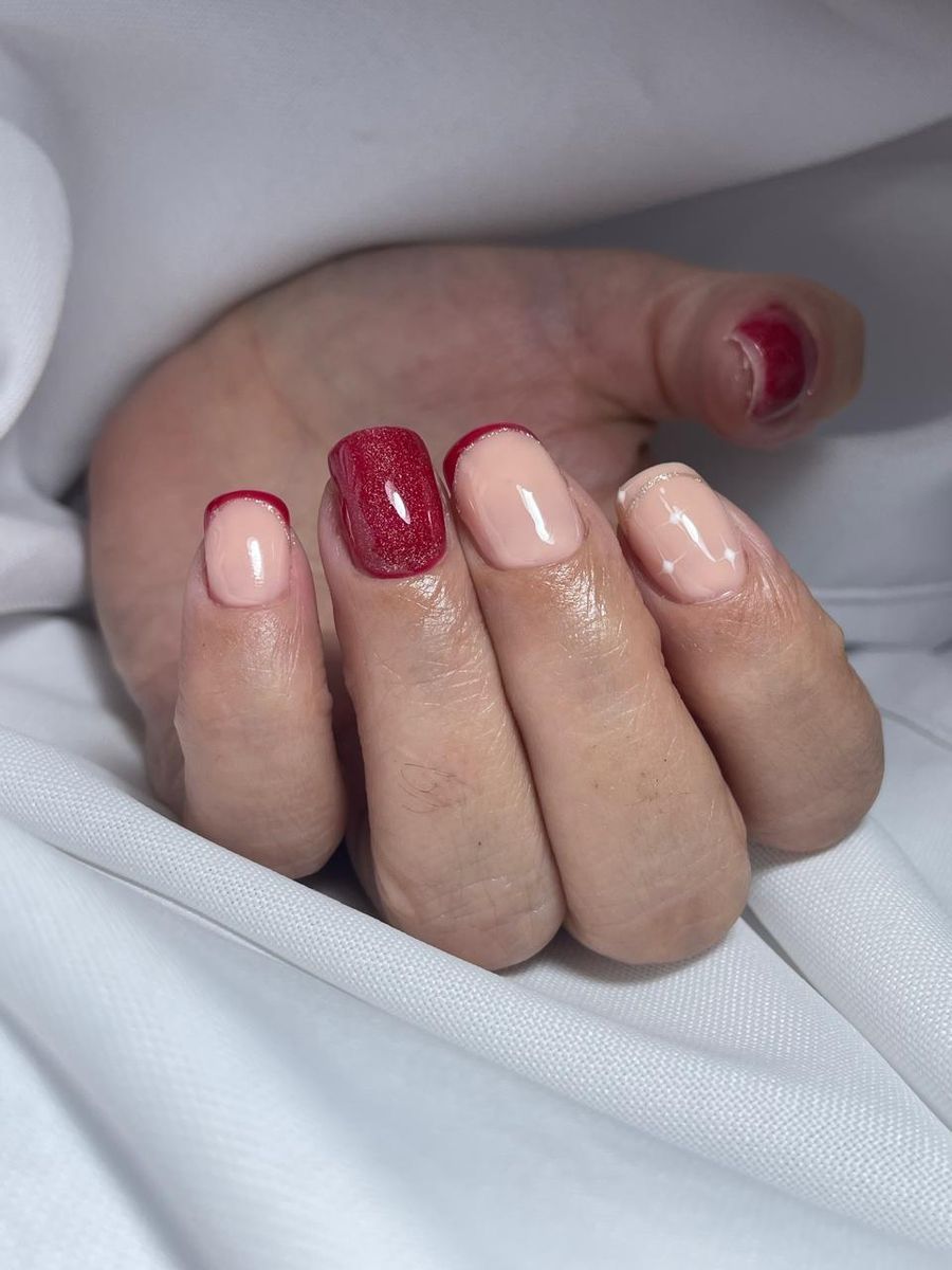 Uñas nude con borde rojo, una con glitter y una con estrellas